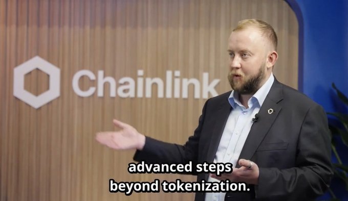 A man in a suit giving a presentation in front of a 'Chainlink' logo backdrop, with subtitles reading 'advanced steps beyond tokenization.'