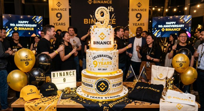 A multi-tiered celebratory cake displays "BINANCE 9 Years" and "CELEBRATING 9 YEARS EST. 2017," surrounded by Binance-branded balloons, hats, and apparel, while employees gather to toast the company's ninth anniversary with "9th ANNIVERSARY" banners in the background. The image visually reinforces the post's message of nine years of innovation and community, capturing the milestone celebration highlighted in the caption.