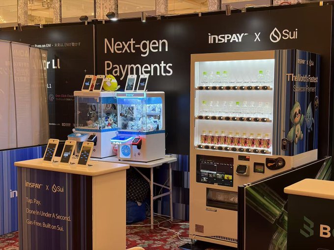 A trade show booth branded 'insPAY X Sui' showcasing 'Next-gen Payments' and a 'World's Fastest Stablecoin Payment' vending machine, featuring a yellow Sui mascot.