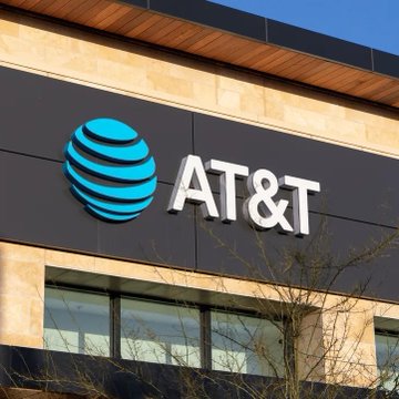 An AT&T store exterior showing the company's blue globe logo and 'AT&T' lettering on a dark gray sign.