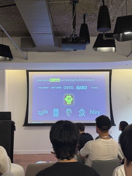 Attendees gather at a pitch event where a presentation slide on "BlinkCashX" is displayed, outlining its mission to build "the first onchain consumer app" that makes account funding as seamless as Apple Pay. The slide features logos of partner brands including Hivemapper (Hivy), suggesting collaborations aimed at reducing friction in blockchain transactions.