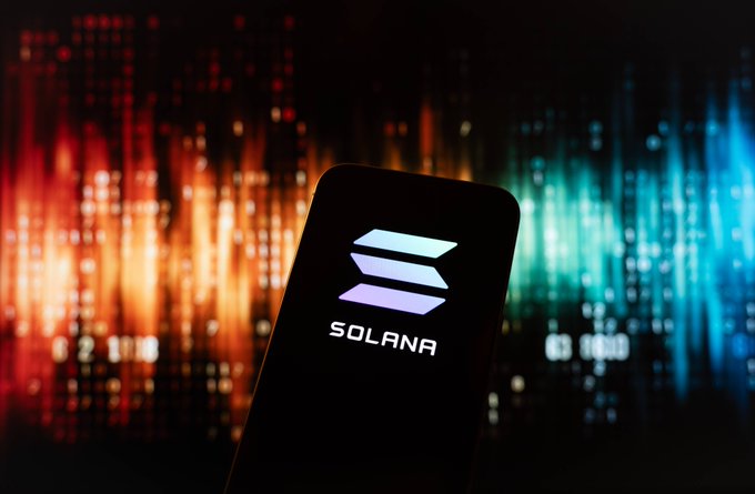 A smartphone displaying the Solana logo against a colorful, blurred background of red and blue lights.
