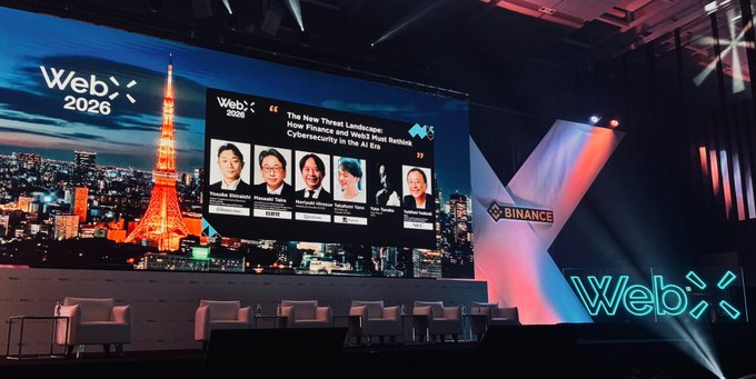 A conference stage at WebX 2026 features a large screen displaying the panel "The New Threat Landscape: How Finance and Web3 Next Bottom Cybersecurity to Do AI Era" with speaker headshots, set against a Tokyo Tower backdrop and prominent Binance and WebX logos. The image reflects the start of the AI cybersecurity session announced for the Binance Stage.