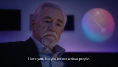 A cinematic still featuring an older bearded man in a suit against a dark blue background with a glowing orb, with subtitles reading 'I love you, but you are not serious people.'