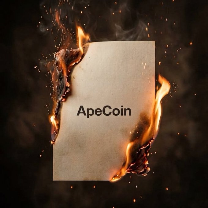 A piece of paper with the text "ApeCoin" is shown burning with flames and smoke surrounding it.
