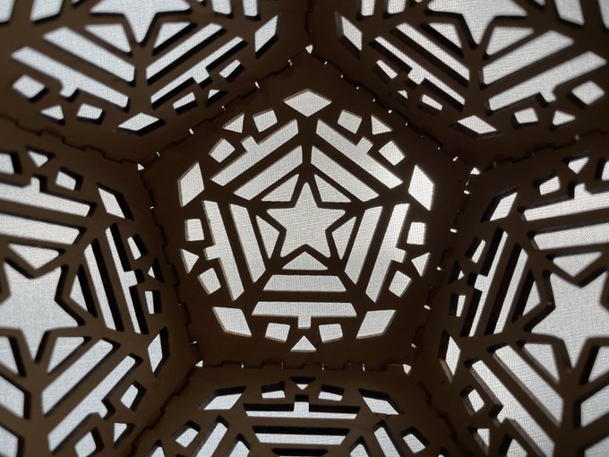 A geometric pattern featuring dark brown stars and intricate shapes on a light textured background, creating a kaleidoscopic star design.
