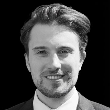 A black-and-white close-up portrait shows a smiling man in a suit, his expression conveying naive enthusiasm that contrasts with the post's dry correction about the difference between running a node and having actual network stake.