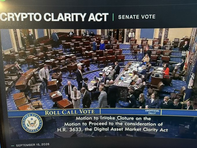 A Senate floor broadcast shows senators gathered on the chamber floor as the "Crypto Clarity Act" banner appears at the top, with an "Unofficial Tally" graphic indicating a "Roll Call Vote" on a "Motion to Invoke Cloture on the Motion to Proceed to the consideration of H.R. 3633, the Digital Asset Market Clarity Act," dated September 15, 2026. The image captures the tense, high-stakes atmosphere of the procedural vote, mirroring the post's comparison to a "life-or-death" moment for crypto legislation.