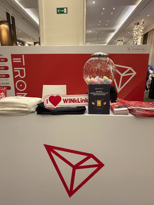 The image features a white counter with various items placed on top of it, including a small glass ball, a book titled "The future of TRON's ecosystem depends heavily on cross-layer integration between DeFi, AI, and real-world data systems". The objects are arranged in such a way that they create an interesting visual composition.