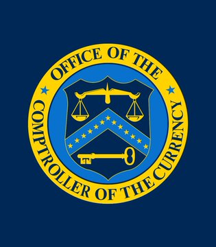 The image shows the official seal of the Office of the Comptroller of the Currency (OCC), featuring a blue shield with scales of justice, a key, and stars, surrounded by a yellow circular border with the text "OFFICE OF THE COMPTROLLER OF THE CURRENCY." The seal relates to the post by highlighting the OCC's role as the federal agency planning to finalize stablecoin regulations and begin accepting crypto license applications, while the CLARITY Act remains stalled in the Senate.