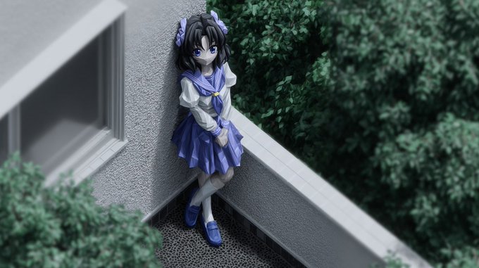 An anime figurine of a dark-haired girl in a blue and white sailor uniform stands posed in the corner of a balcony with a miniature green tree next to her.