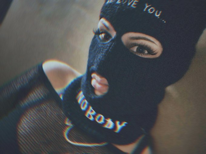 A stylized photo of a woman wearing a black ski mask with 'LOVE YOU...' written on the forehead area and 'NOBODY' on the chin strap.