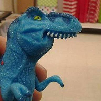 A hand holds up a small blue plastic dinosaur toy with sharp white teeth and yellow eyes. The image appears alongside a Chinese post discussing stablecoins like #FEFER and #STABLE, with the dinosaur possibly serving as a mascot or symbol for one of these crypto projects.