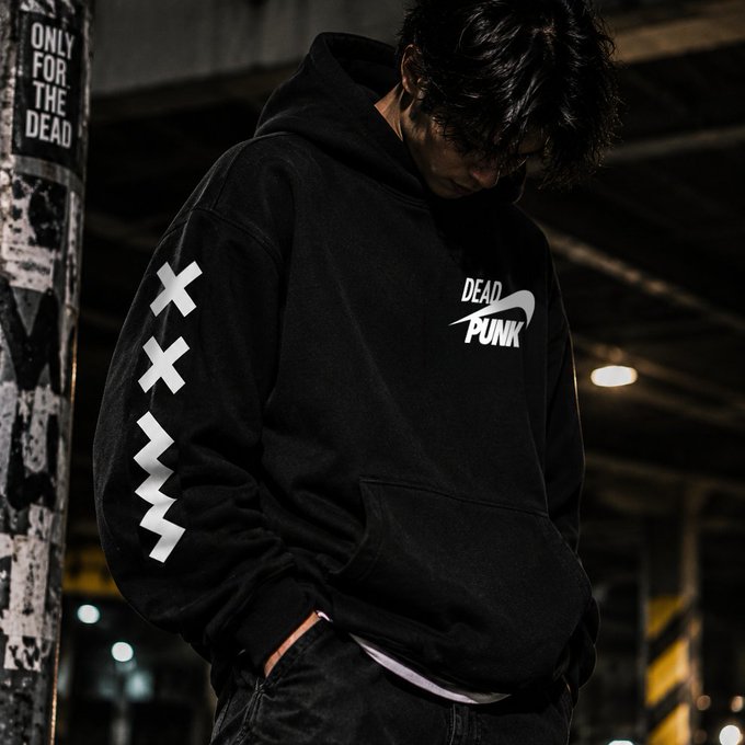 Photo of a person wearing a black 'DEAD PUNK' hoodie with white X sleeve graphics, standing next to a pole labeled 'ONLY FOR THE DEAD' in a dark industrial setting.