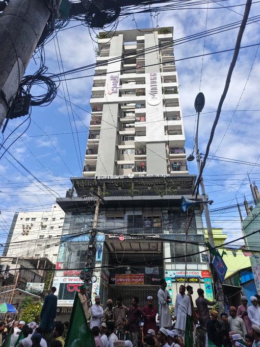 A crowd gathers outside a multi-story building marked "Momtas Tower," with a "Beldex Office" sign visible on the ground floor, suggesting a community event at the Beldex cryptocurrency office.
