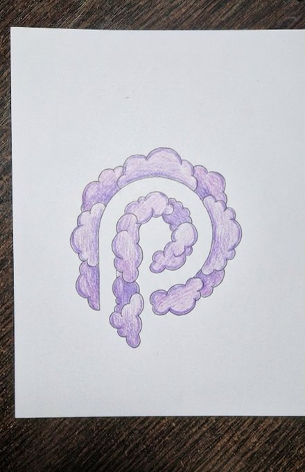 The image features an illustration of a purple cloud-like shape that resembles the letter "P" with a line extending from its center. The cloud-like shape is positioned centrally, occupying most of the space within the frame. The background appears to be a wooden surface or table, providing a simple yet effective backdrop for the drawing.