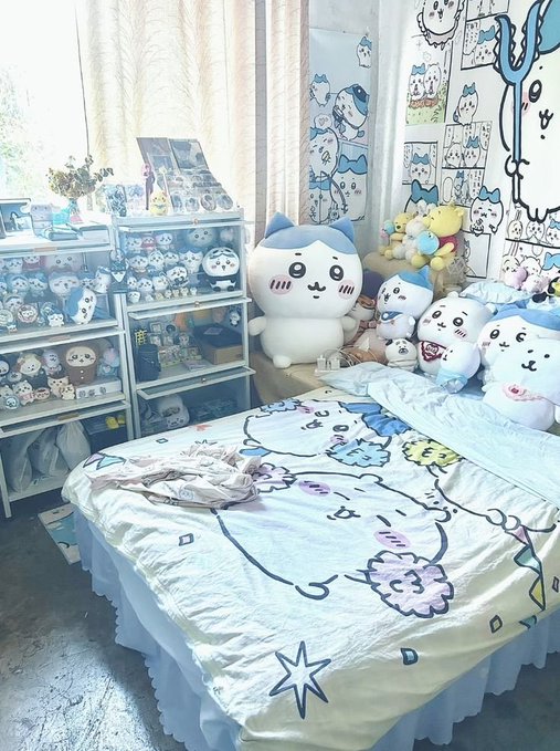 A cozy bedroom is decorated with numerous Chiikawa character merchandise, including plush toys displayed on shelves and a bed covered with matching Chiikawa-themed bedding and pillows. The image reflects the popular Japanese kawaii franchise's growing retail presence, showing how fans create dedicated themed spaces filled with character collectibles.