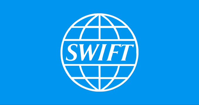 The blue logo features "SWIFT" in bold white lettering across a stylized white globe with meridian lines. The image ties to the caption's discussion of SWIFT's "Policy Lab" potentially connecting XRP as a bridge asset with SWIFT's messaging infrastructure through partners like Thunes.
