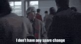 The image shows a group of people standing next to each other, with one person wearing a tie. There are at least ten people visible in the scene. The text "I don't have any spare change" is written below them, which appears to be part of an advertisement or social media post. The focus on this message and its placement within the image suggests that it might be related to a product or service being advertised.