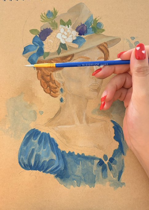 A watercolor painting in progress of a woman wearing a flower-adorned hat and blue dress, with a hand holding a Bleiswijk brush visible in the foreground.