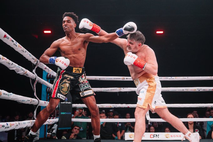 Two boxers battle in the ring, with the shorter fighter on the left in black-and-gold "BONX" trunks dodging a high punch from his taller opponent in white trunks, while ring ropes display "BONK," "CFN," and "KICK.COM" branding—visually echoing the "new challenger" vibe of the pump.fun token post.