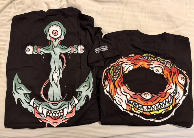Two black t-shirts are laid out on a striped surface, each featuring Bored Ape Yacht Club (BAYC) artwork—one depicting a green ape-headed figure atop a monster, and the other a flaming circular ape skull design—with the accompanying post teasing the release as "Clothing drop 1/4 this week #mayc #bayc," indicating this is a preview of a limited apparel launch for the NFT collection.