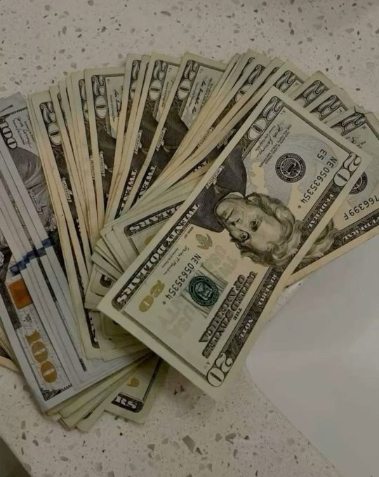 The image shows a fanned-out stack of U.S. $50 bills spread across a speckled countertop, with serial numbers like NE0656351F visible on the top bills. The arrangement of cash visually represents the "money making opportunities" referenced in the post, serving as a symbolic display of wealth and financial success.