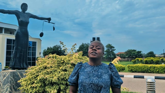 A woman stands in front of a Lady Justice statue holding scales, with a cloudy blue sky in the background. The image appears unrelated to the post about cryptocurrency limit orders on Base App, though it symbolically represents themes of fairness and balance that could loosely connect to trading concepts.