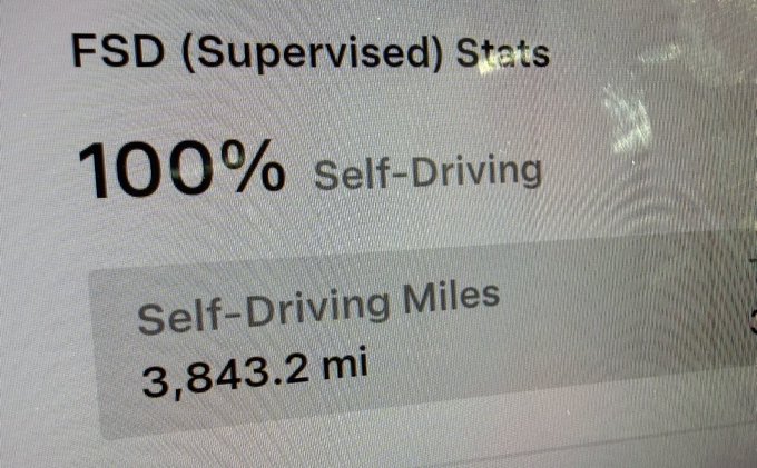 A close-up of a Tesla screen displaying 'FSD (Supervised) Stats' showing '100% Self-Driving' and 'Self-Driving Miles 3,843.2 mi'.