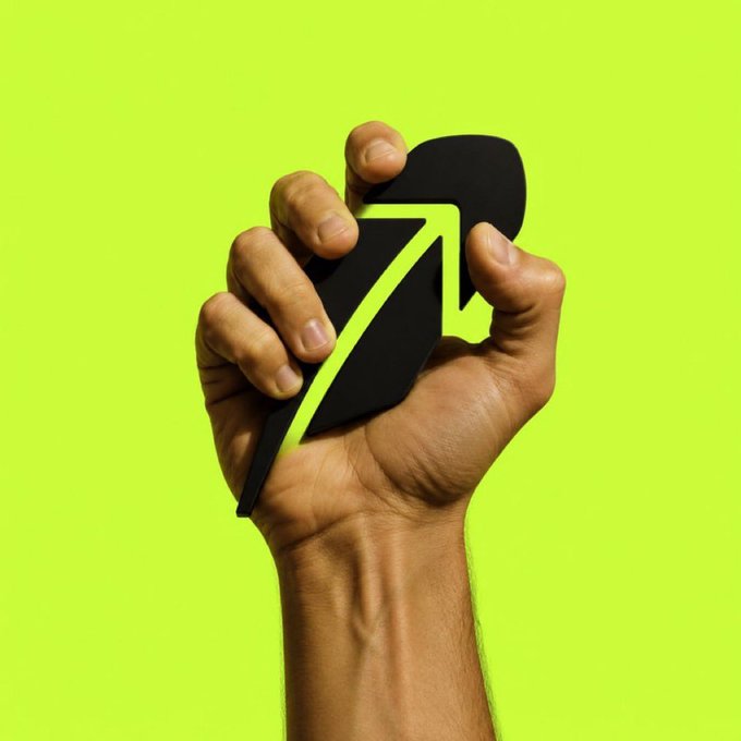 A close-up of a hand squeezing a cracked black heart with a bright green upward arrow growing out of it against a neon green background.