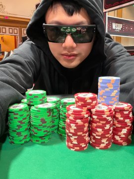A poker player wearing sunglasses and a black hoodie sits behind large stacks of green and red poker chips with a celebratory post about surviving "Day 5" and advancing to "Day 6" of a tournament with 174 players remaining, visually representing his chip stack at the event (likely WSOP, as suggested by the partial sign in the background).