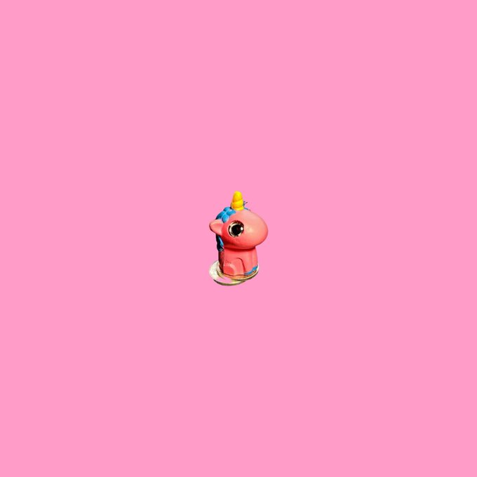 A small pink unicorn figurine centered against a solid pink background.