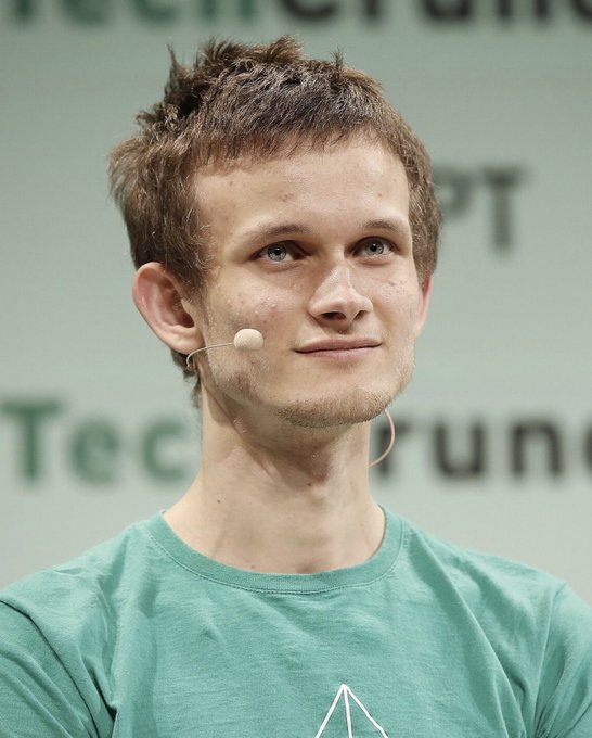 A portrait of Vitalik Buterin speaking onstage, wearing a headset microphone and a green T-shirt. It illustrates the accompanying post’s claim that he wrote Bitcoin articles as a teenager, later wrote the Ethereum whitepaper at age 19, and highlights “5 BTC” as the payment mentioned.