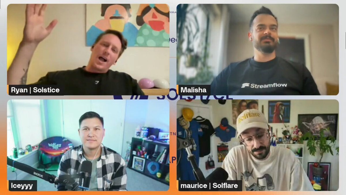 The image shows four men sitting around a table with their hands raised, appearing engaged in an online meeting or discussion. The background of the image features a painting that includes a woman's face, adding a creative touch to the scene. The men are wearing t-shirts and hats, suggesting they might be participating in a casual gathering or event.