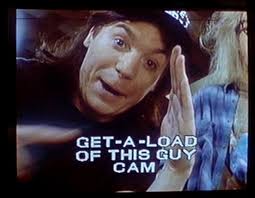 A vintage-style camcorder frame showing a young man with a surprised expression next to the text 'GET-A-LOAD OF THIS GUY CAM'.