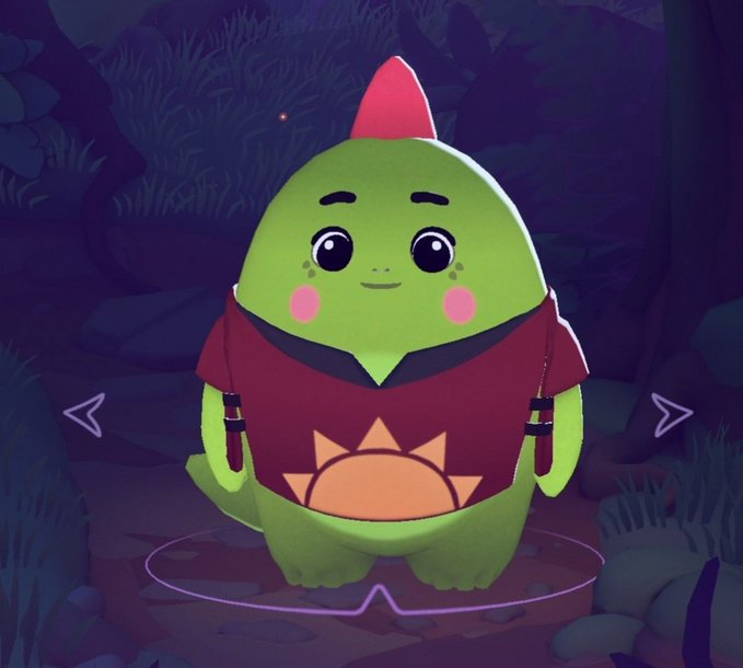 A cute green cartoon character with a red fin, wearing a maroon shirt with a sun design, standing in a dimly lit forest setting with navigation arrows on either side.