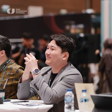 A man in a gray blazer sits at a table with his hands clasped, wearing a watch, with a 'C' logo for 'Cobo Institutional Partners' visible in the corner.
