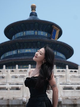 A woman in a black strapless dress posing in front of the Temple of Heaven (Tiantan) in Beijing, China.