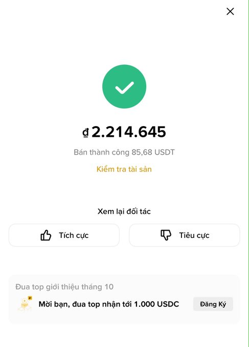 A Binance cashout confirmation showing ₫2,214,645 (VND) received from a successful sale of 85.68 USDT, with options to review the counterparty and a promotional banner inviting users to join October's top referral leaderboard for 1,000 USDC.