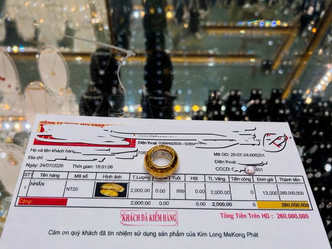 A Vietnamese gold receipt from a jewelry company showing a purchase of 2 tael (NT20) of 'NHẪN' (ring) totaling 260,000,000 VND, with a gold ring placed on the receipt.