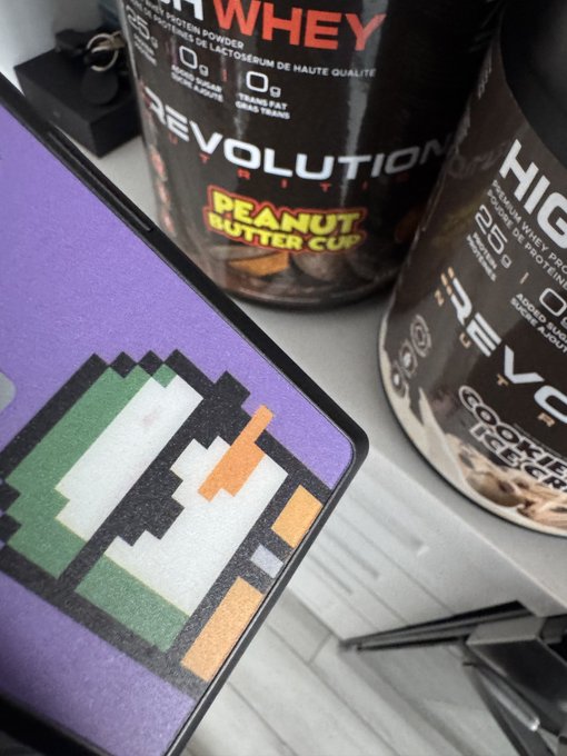 A close-up shot of a pixel-art desk mat alongside Revolution Nutrition whey protein tubs labeled "PEANUT BUTTER CUP" and "COOKIE & CREAM," evoking a "Fresh Week, Fresh Opportunities" vibe for fitness and gaming enthusiasts ready to start strong.