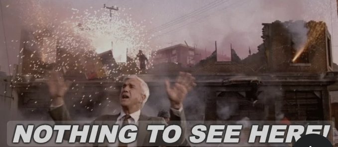A dramatic movie still showing a man raising his hands in surrender amid sparks and rubble, overlaid with the caption 'NOTHING TO SEE HERE!'.
