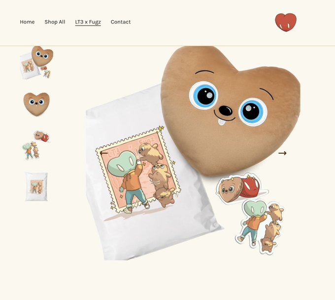 An online merchandise page displays the 'LT3 x Fuggz' collection featuring a heart-shaped plush pillow with a smiling face, a white printed bag, and stickers.