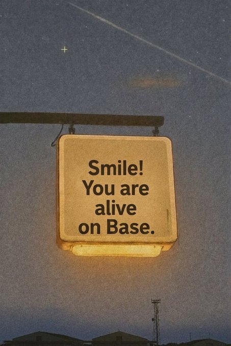 An illuminated sign reading 'Smile! You are alive on Base.' mounted under a night sky with a shooting star.