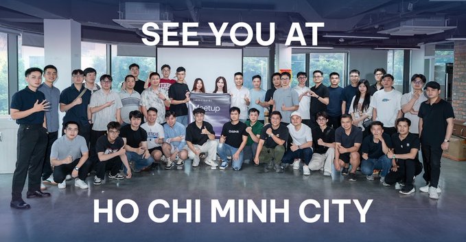 Group photo of meetup attendees with overlaid text reading "SEE YOU AT HO CHI MINH CITY," featuring a "Meetup" banner in the center.