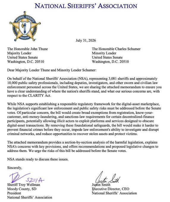 The image shows an official letter dated July 31, 2026, from the National Sheriffs' Association to Senate Majority Leader John Thune and Minority Leader Charles Schumer, expressing support for establishing a digital-asset regulatory framework through the CLARITY Act but raising concerns that the bill's broad exemptions for decentralized-finance participants could enable illicit actors to evade registration and anti-money-laundering requirements. Signed by Sheriff Troy Wellman (President) and Justin Smith (Executive Director/CEO), the letter outlines law enforcement concerns and proposes legislative amendments—directly supporting the accompanying post's claim that sheriffs are demanding stronger protections before the Senate votes on the bill.