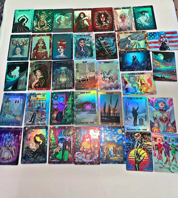 A spread of approximately 40 colorful tarot-style art cards titled "#GGArtMaster" Series 1, displayed on a white surface as proof of the creator's independent NFT/tarot project. The cards feature various artistic illustrations including figures, landscapes, and symbolic imagery (with visible titles like "The Lovers," "America," "Garten Death," and "What is Your Dream"), showcasing the self-funded collaboration with international artists mentioned in the post.