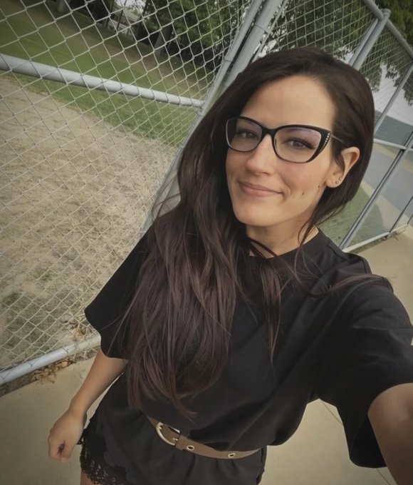 A woman in black glasses and clothing smiles for a selfie beside a chain-link fence. The peaceful, low-key setting complements the post’s message about valuing peace, privacy, and saying “no.”