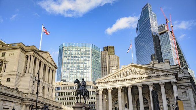The image shows the Bank of England and the Royal Exchange in the City of London, with skyscrapers including Heron Tower (110 Bishopsgate) towering behind them, framing a scene of traditional British finance against a modern skyline. This iconic financial district setting visually underscores the article's announcement that major UK banks—Lloyds, NatWest, Barclays, and HSBC—have pioneered blockchain-based tokenized deposit transactions, marking a historic modernization of the very heart of British banking depicted here.