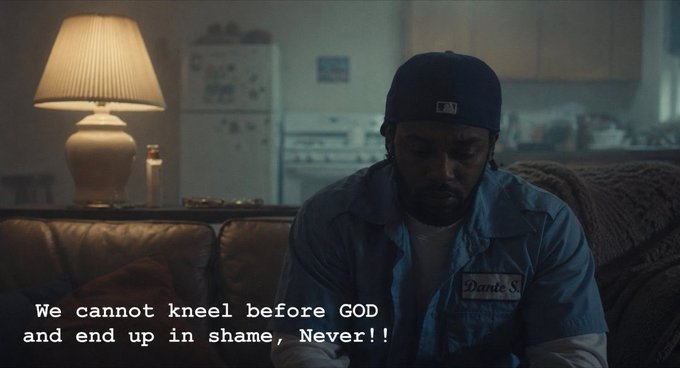 A screenshot from a movie or TV show showing a man in a beanie and blue work shirt sitting in a dimly lit room, with the caption 'We cannot kneel before GOD and end up in shame, Never!!'